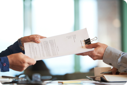Deux personnes s'échangeant un document officiel sur un bureau, illustrant la remise d'un certificat d'étanchéité F-Gaz ou la signature d'un contrat de maintenance de climatisation à Béziers.